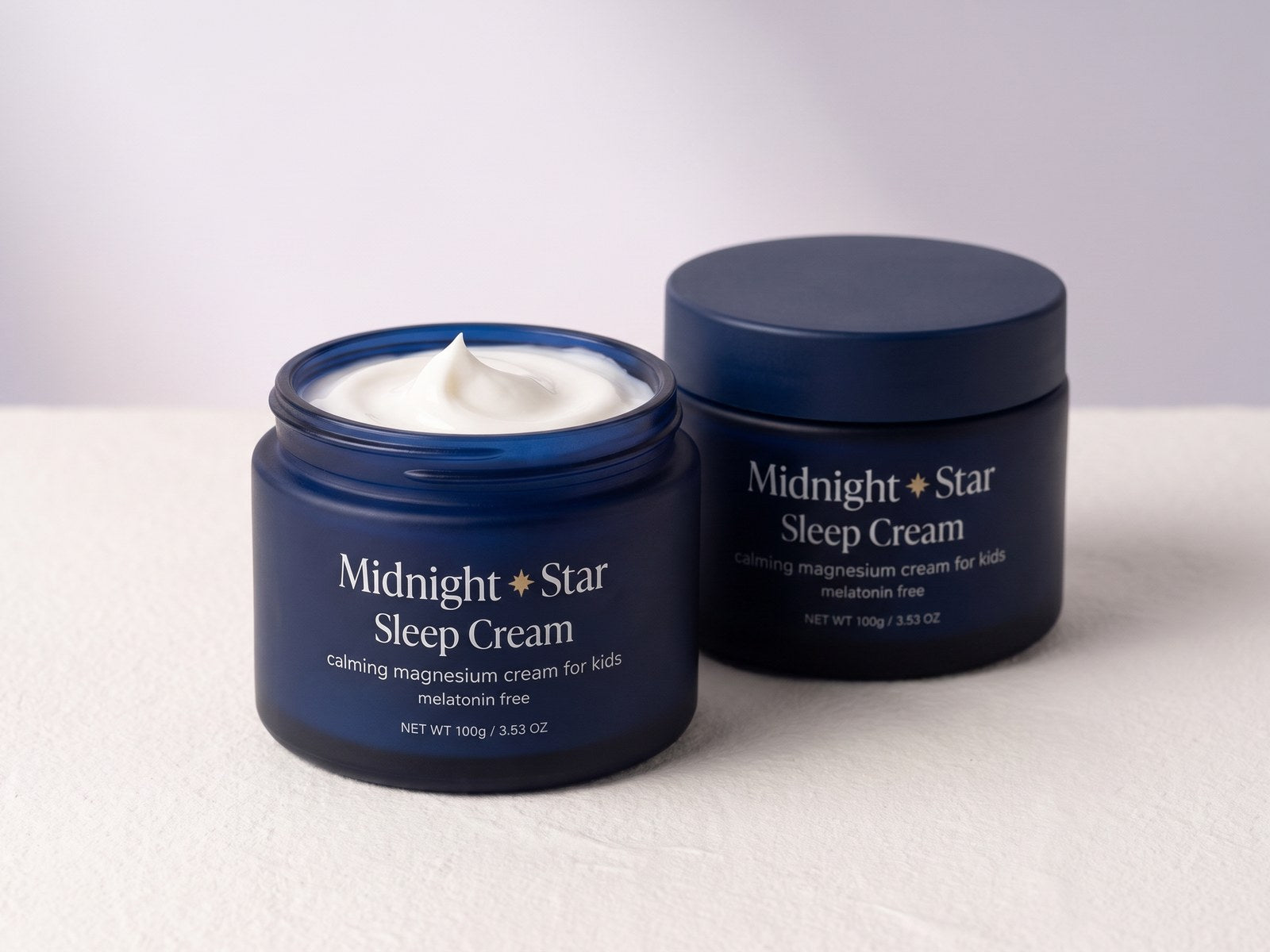 Two jars of Midnight and Star Sleep Cream side by side, the front one open showing the cream inside