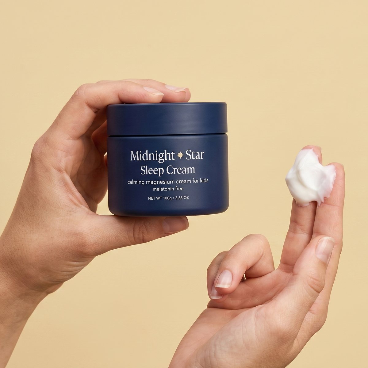 A hand holding the tub, with a scoop of the cream on two fingers