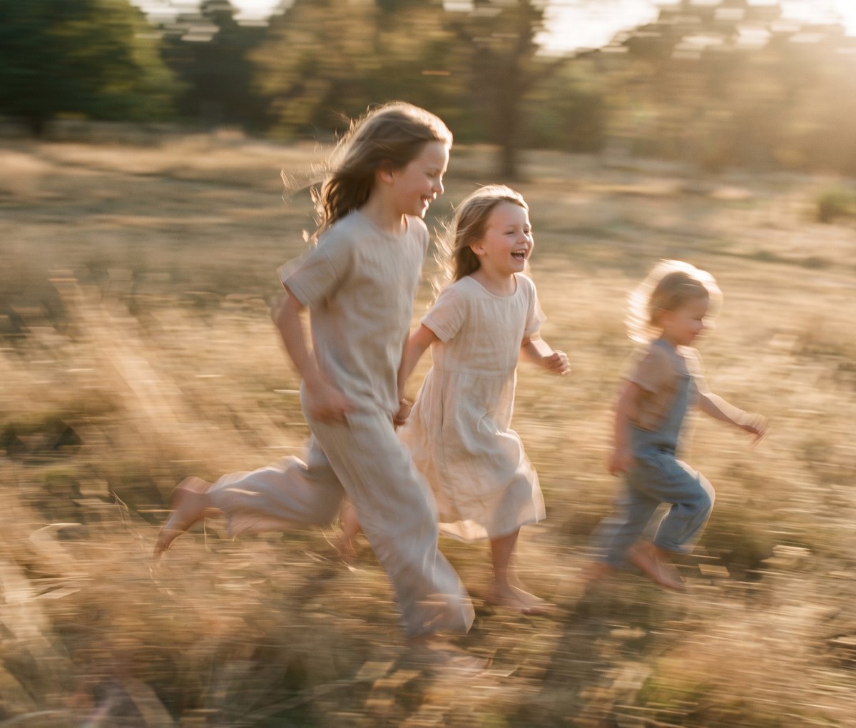 Three children running through sunlit grass